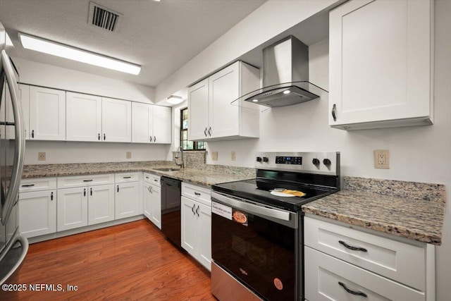 kitchen featuring visible vents, appliances with stainless steel finishes, wall chimney exhaust hood, and white cabinets