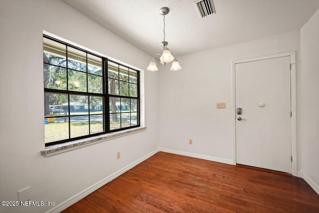 interior space with visible vents, baseboards, wood finished floors, a notable chandelier, and a textured ceiling