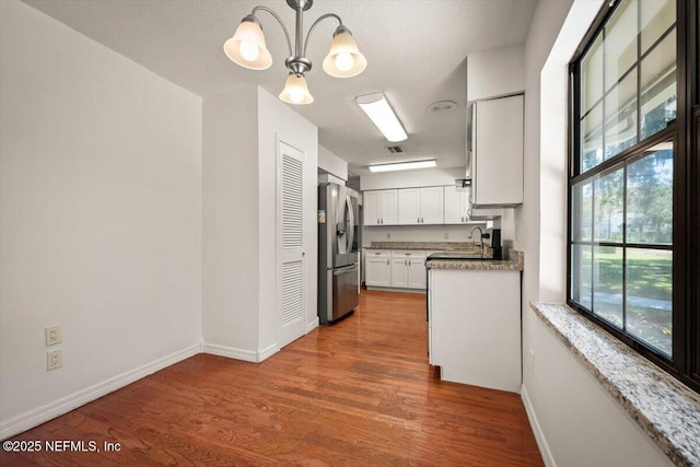 kitchen with a notable chandelier, a sink, wood finished floors, and stainless steel fridge with ice dispenser