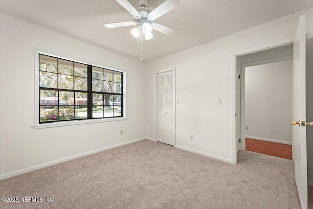 unfurnished bedroom with a closet, baseboards, ceiling fan, and carpet flooring