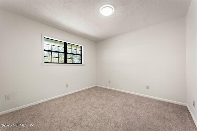 carpeted spare room featuring baseboards and a textured ceiling