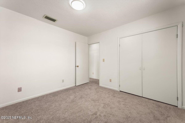 unfurnished bedroom with visible vents, baseboards, carpet, a closet, and a textured ceiling