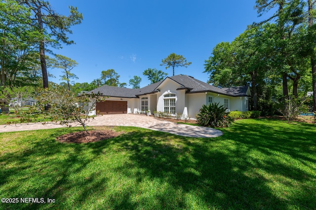 single story home with a garage, stucco siding, a front yard, and decorative driveway