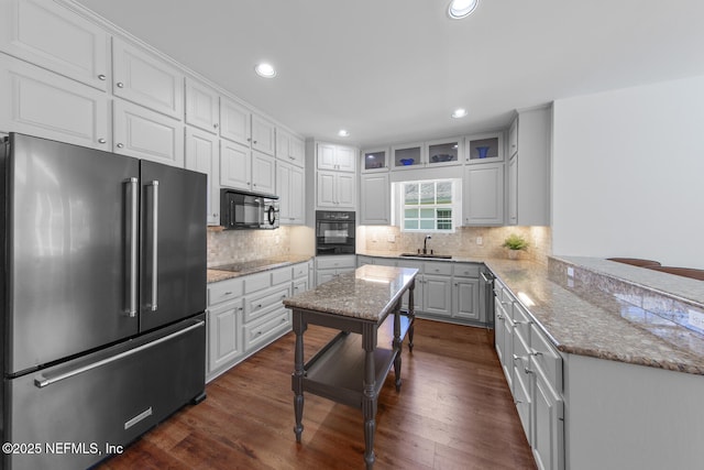 kitchen with dark wood-type flooring, tasteful backsplash, black appliances, and recessed lighting