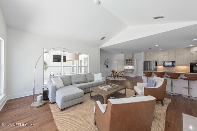 living room with visible vents, baseboards, wood finished floors, and lofted ceiling