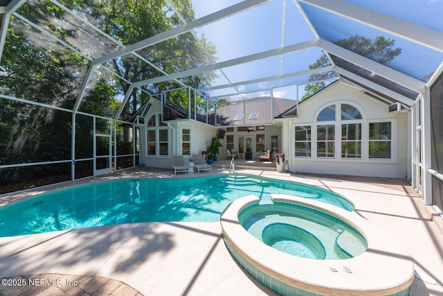 view of swimming pool featuring a patio area, a pool with connected hot tub, and glass enclosure