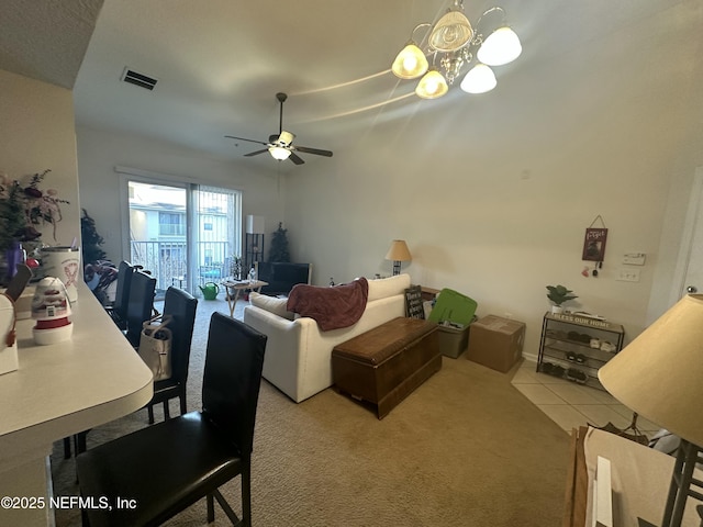 carpeted living room with tile patterned flooring, visible vents, and ceiling fan with notable chandelier