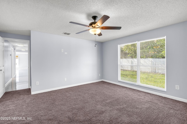 spare room featuring visible vents, baseboards, ceiling fan, dark carpet, and a textured ceiling