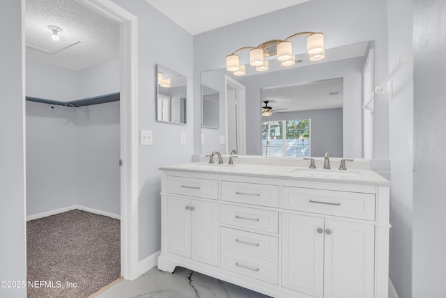 bathroom featuring ceiling fan, double vanity, a textured ceiling, and a sink