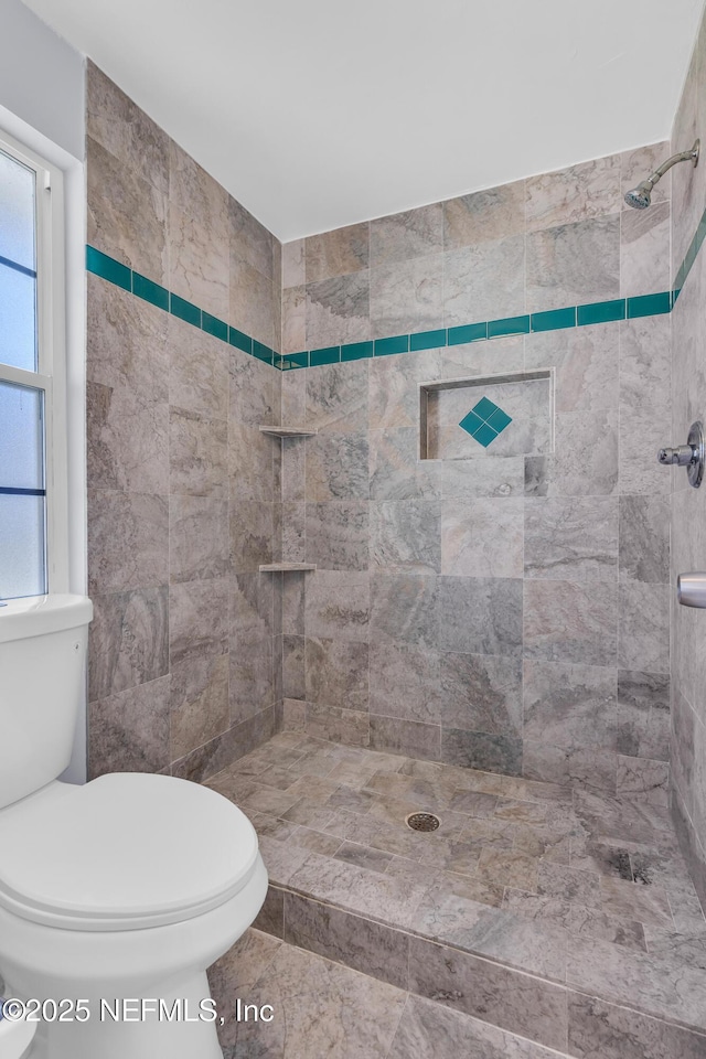 bathroom featuring tiled shower and toilet