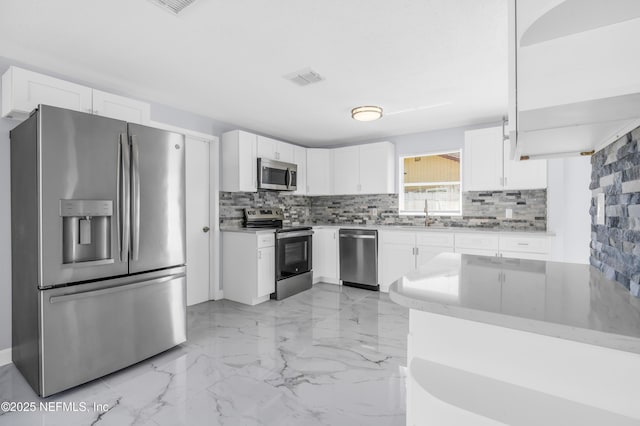 kitchen with visible vents, marble finish floor, backsplash, white cabinetry, and appliances with stainless steel finishes