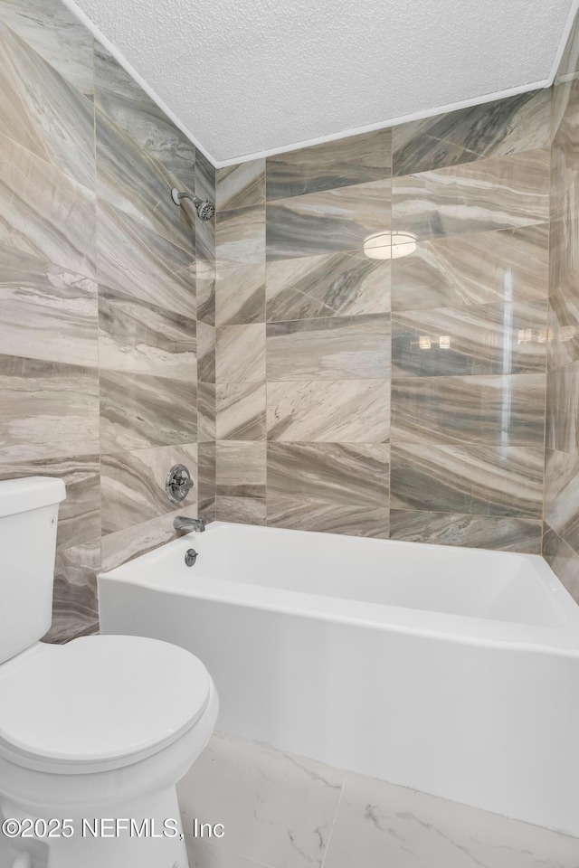 full bathroom with  shower combination, a textured ceiling, tile walls, toilet, and marble finish floor