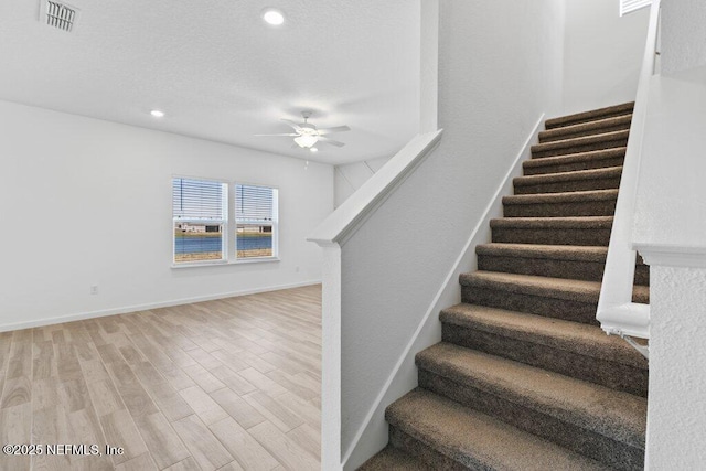 stairs featuring visible vents, a ceiling fan, a textured ceiling, wood finished floors, and baseboards