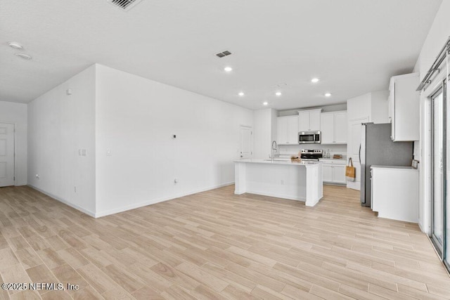 kitchen with light wood-type flooring, visible vents, open floor plan, stainless steel appliances, and light countertops