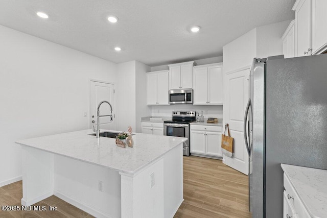 kitchen with a sink, recessed lighting, appliances with stainless steel finishes, white cabinets, and light wood finished floors