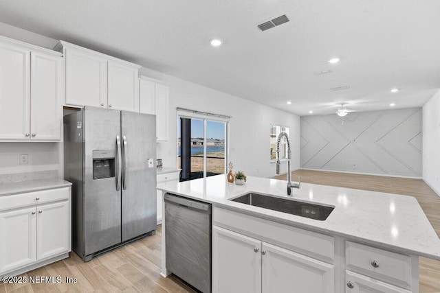 kitchen with light wood finished floors, visible vents, appliances with stainless steel finishes, white cabinets, and a sink