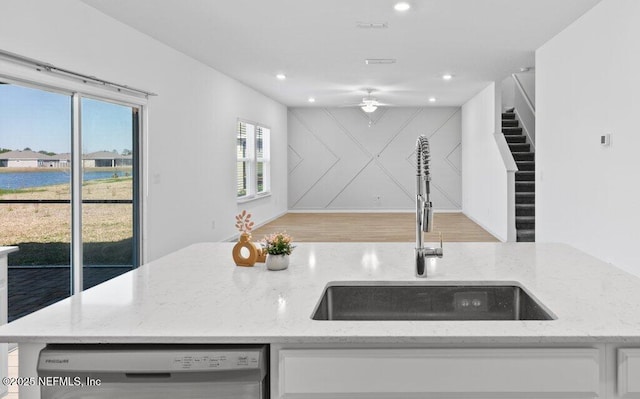 kitchen featuring stainless steel dishwasher, white cabinets, a ceiling fan, and a sink