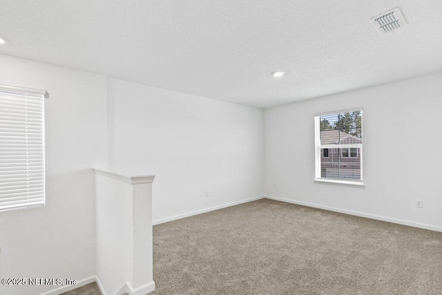 empty room featuring carpet flooring, visible vents, and a textured ceiling