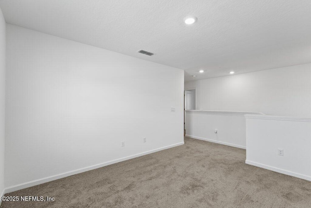 carpeted spare room featuring visible vents, recessed lighting, a textured ceiling, and baseboards