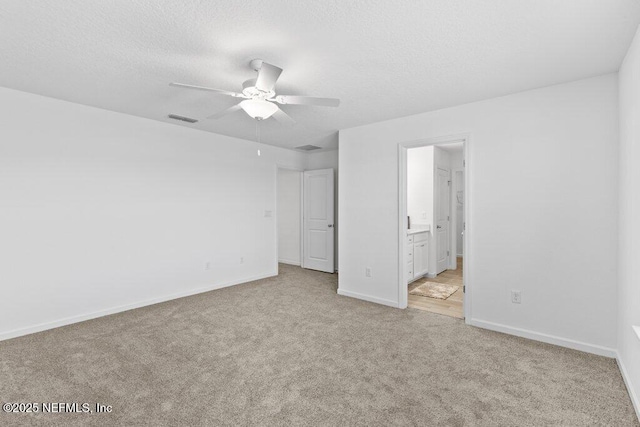 unfurnished bedroom with baseboards, visible vents, ensuite bathroom, a textured ceiling, and carpet flooring