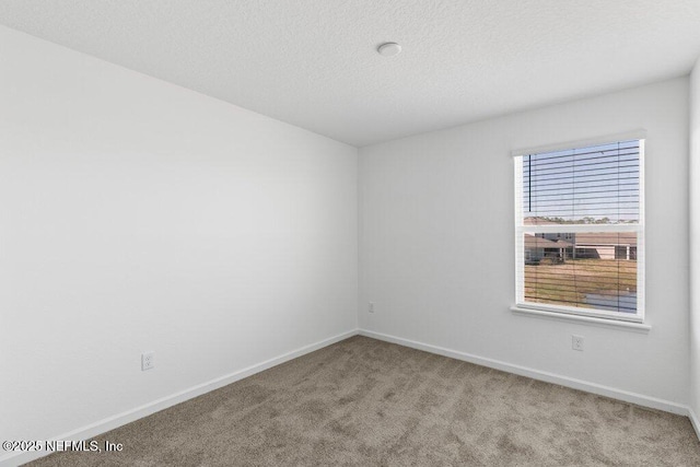 carpeted spare room featuring a textured ceiling and baseboards