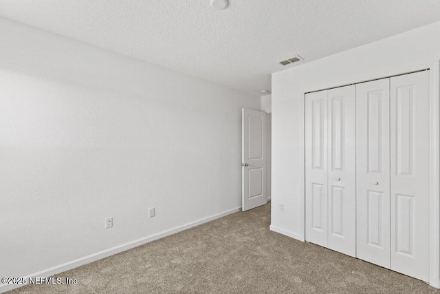 unfurnished bedroom featuring visible vents, baseboards, carpet, a closet, and a textured ceiling