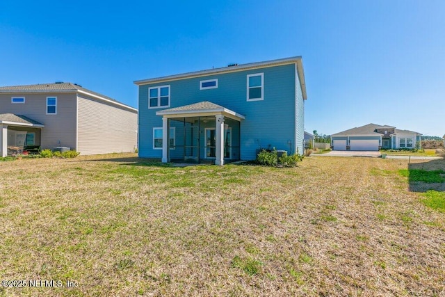 back of property featuring an outbuilding, a yard, and a sunroom