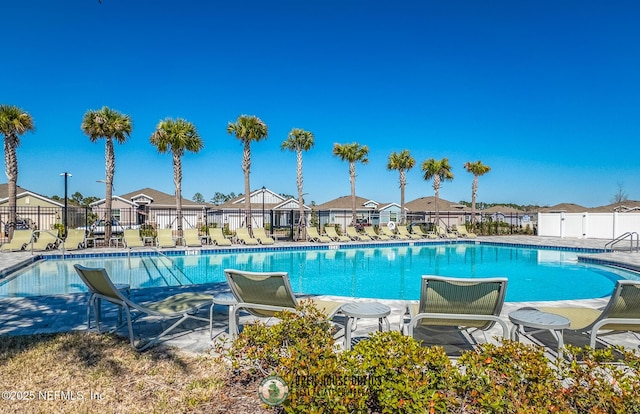 community pool with a patio area, fence, and a residential view