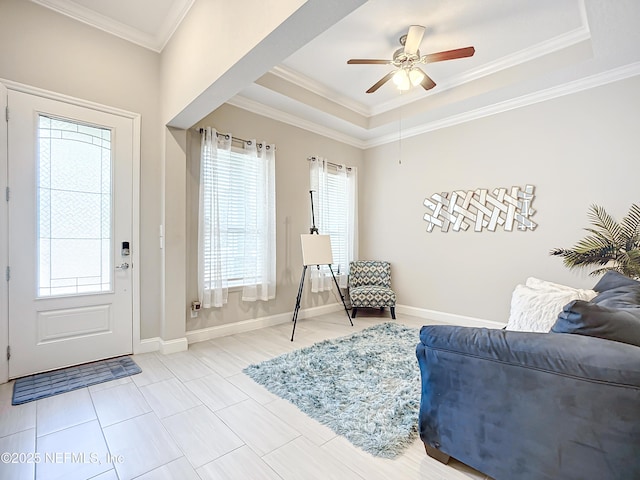 foyer entrance featuring a ceiling fan, a tray ceiling, crown molding, and baseboards