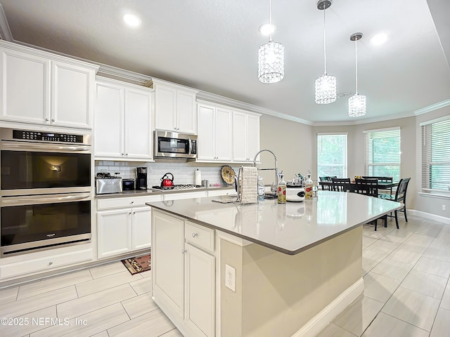 kitchen with tasteful backsplash, crown molding, hanging light fixtures, white cabinets, and stainless steel appliances