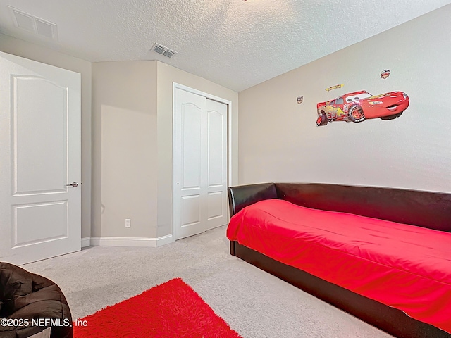 bedroom with visible vents, carpet, a closet, and a textured ceiling