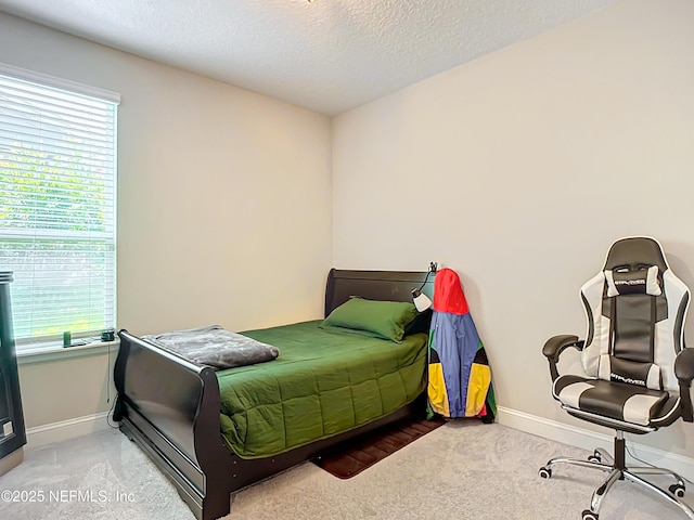 carpeted bedroom with multiple windows, a textured ceiling, and baseboards