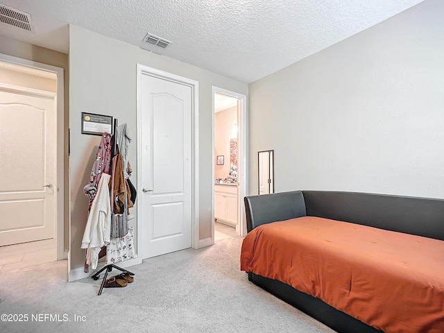 bedroom featuring light carpet, visible vents, connected bathroom, and a textured ceiling