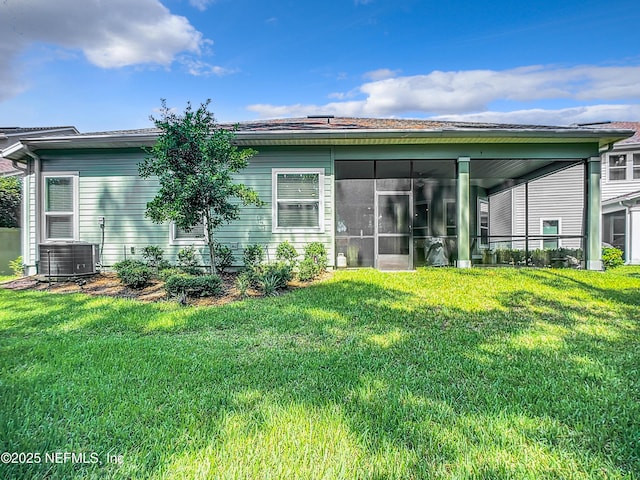 rear view of property with central air condition unit, a lawn, and a sunroom