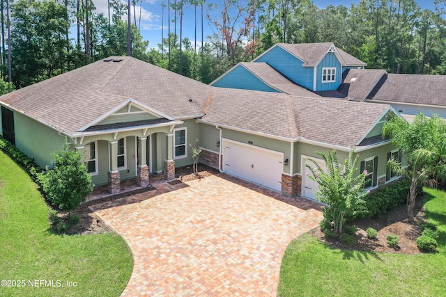 craftsman house with roof with shingles, a porch, a front lawn, stone siding, and a garage