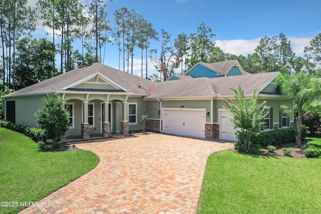 craftsman-style home with roof with shingles, a porch, a front lawn, a garage, and decorative driveway