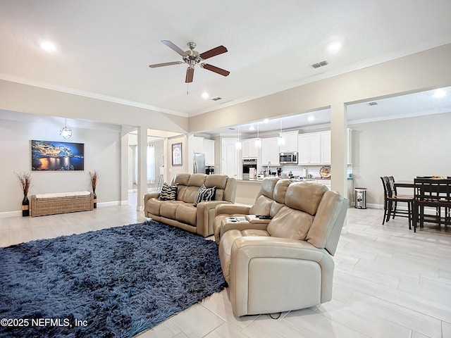 living area featuring visible vents, baseboards, ceiling fan, and crown molding