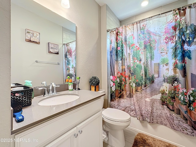 full bath featuring vanity, toilet, and a textured wall