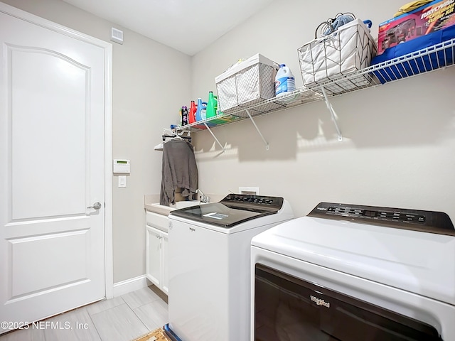 clothes washing area with washing machine and clothes dryer, cabinet space, baseboards, and a sink