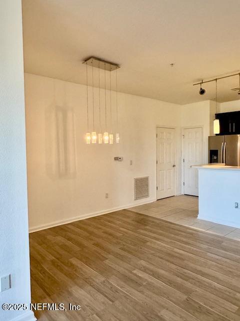 interior space with rail lighting, baseboards, visible vents, and light wood finished floors