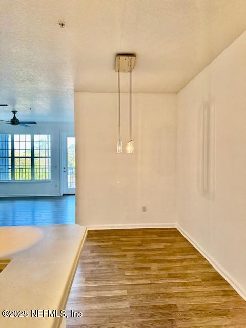 unfurnished room featuring baseboards, a textured ceiling, wood finished floors, and a ceiling fan