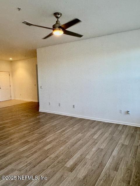 spare room with visible vents, baseboards, wood finished floors, and a ceiling fan