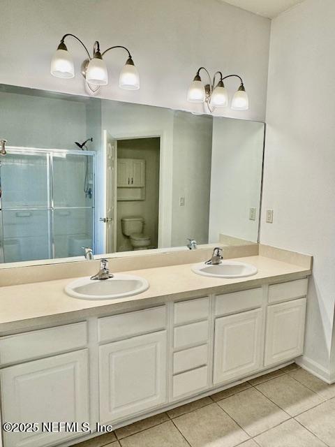 full bath featuring a sink, toilet, a shower stall, and tile patterned flooring