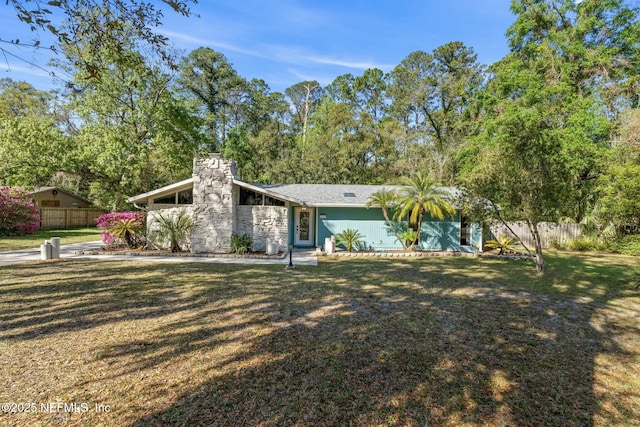 mid-century home with a front yard, a chimney, and fence