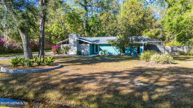 view of front facade with a chimney, a front yard, and fence