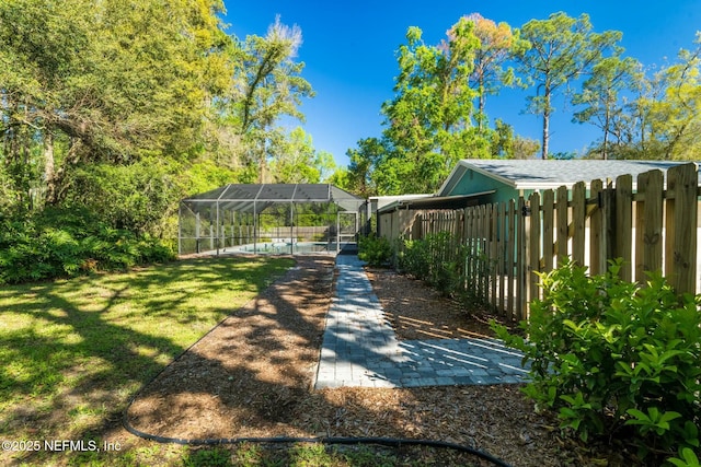 view of yard with glass enclosure, an outdoor pool, and fence