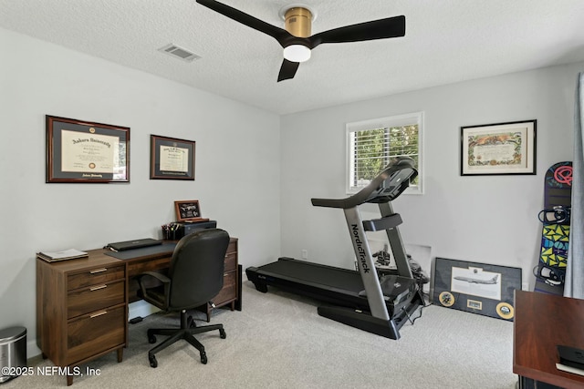 office space featuring visible vents, light colored carpet, ceiling fan, and a textured ceiling