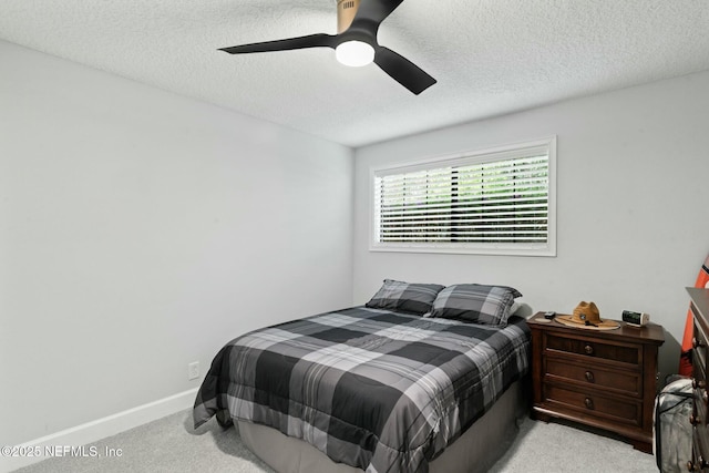 carpeted bedroom featuring baseboards, a textured ceiling, and a ceiling fan