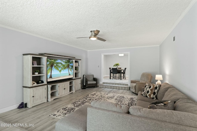 living room with crown molding, baseboards, ceiling fan, light wood-style floors, and a textured ceiling