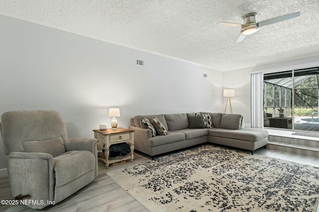 living area featuring visible vents, a textured ceiling, a ceiling fan, and wood finished floors